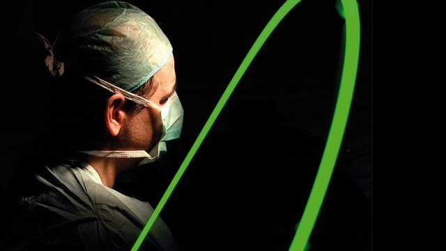 Imagen del doctor Sanz de espaldas, se muestra junto a un láser verde